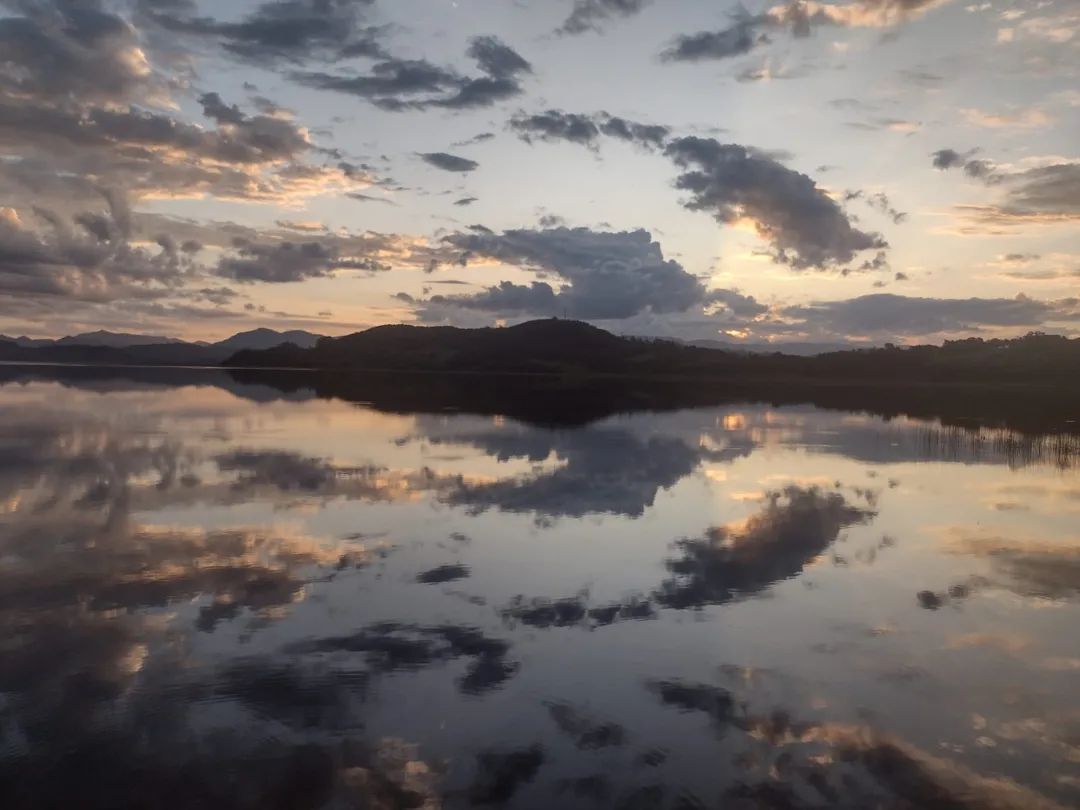 Nuvens e morros refletindo na água da Lagoa Itapeva (em Torres), num final de tarde (FOTO por Felipe Araujo Santos)